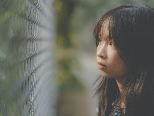thoughtful asian girl looking through grid