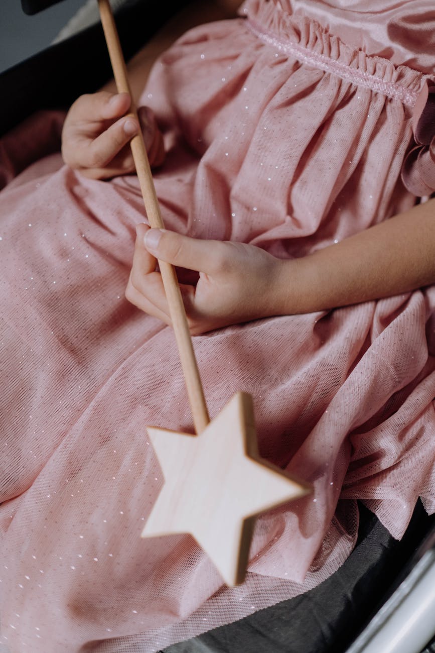 a girl wearing a pink dress holding a magic wand