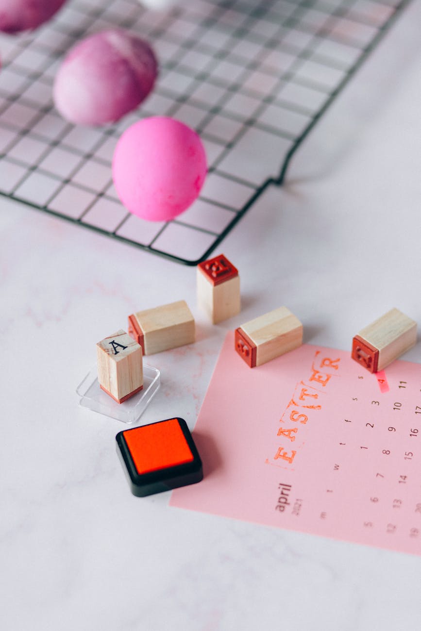 pink eggs and brown wooden blocks with stamp beside a pink calendar