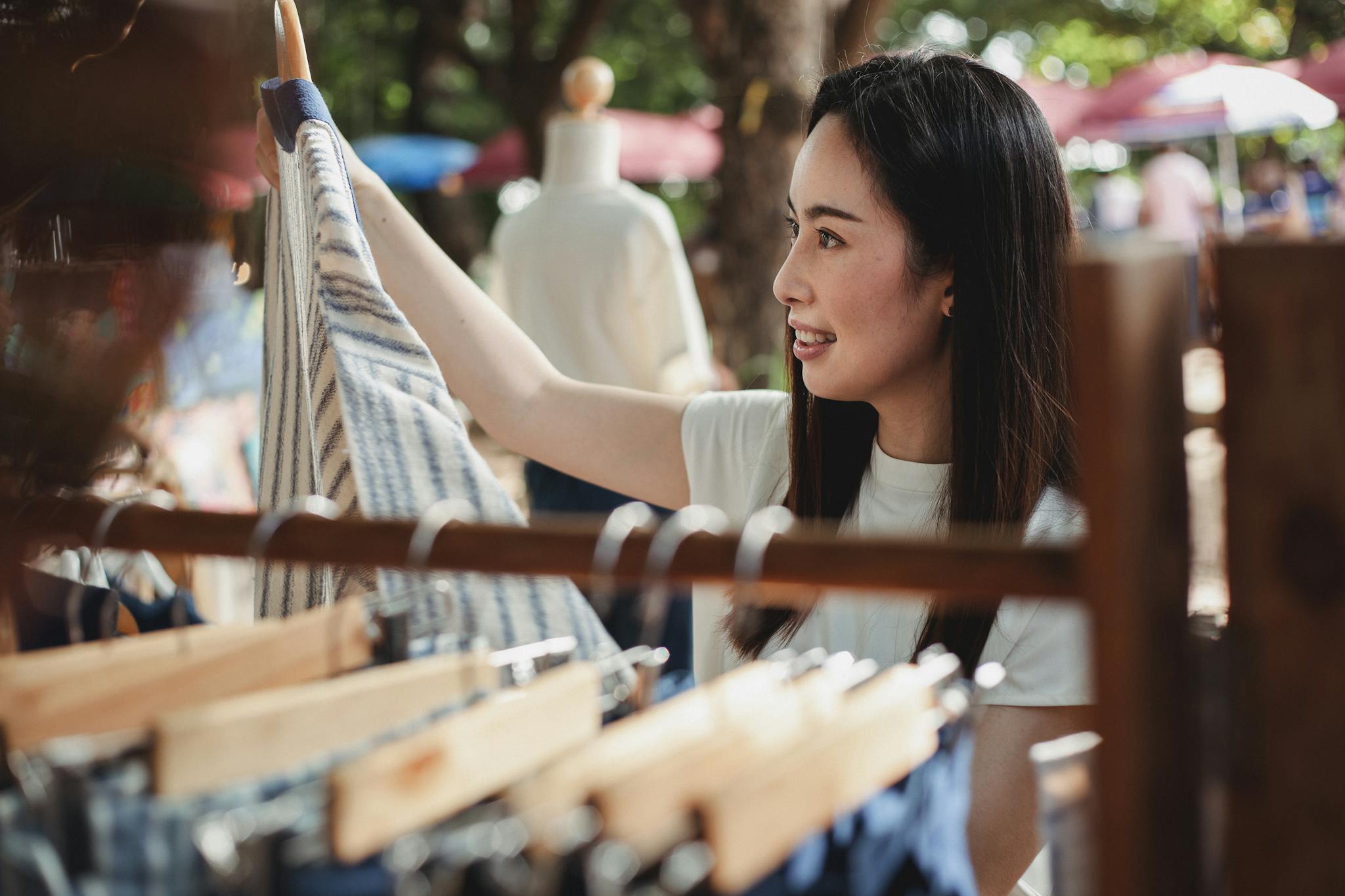Young Asian woman shopping at an outdoor market stall in the summer.